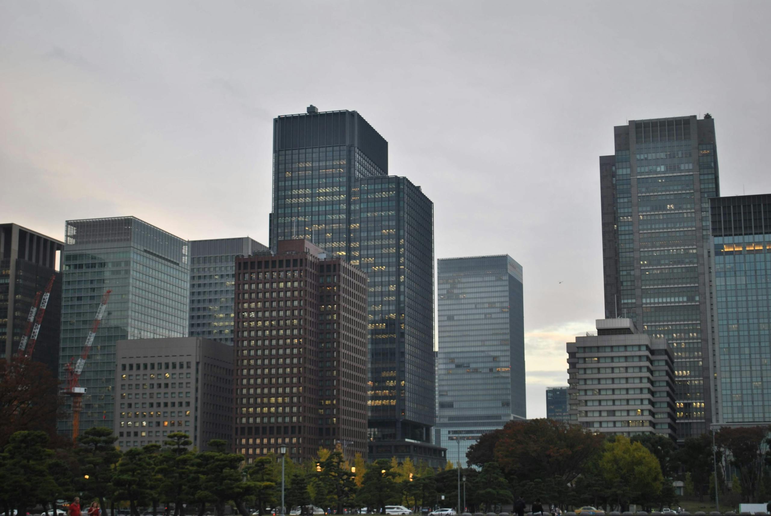 Cityscape view of modern skyscrapers at dusk, with a blend of architectural styles and cloudy sky.